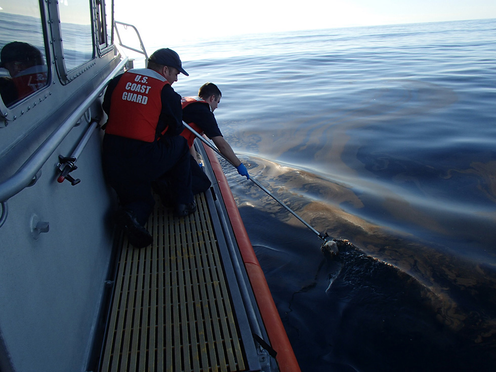 Two men on boat's deck taking water samples. Image USCG.